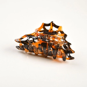 Detailed close-up of tortoise shell hollow spider web hair claw clip with acetate texture