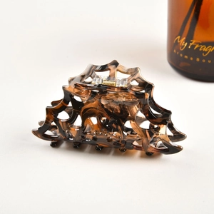 Close-up of a tortoiseshell hair claw clip with cutout geometric design and golden spring