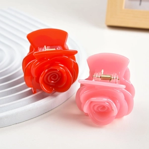Detailed close-up of rose flower hair claws in red and pink acetate finish