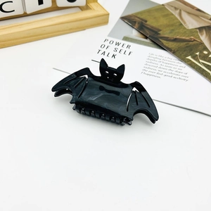 Macro detail of a black bat-shaped hair claw clip with marble texture for Halloween
