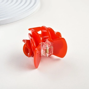 Close-up of a glossy red rose hair claw clip with detailed resin petals and spring mechanism