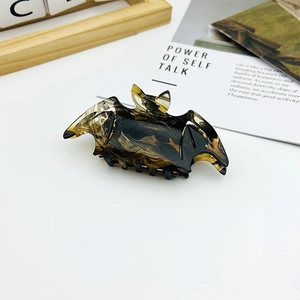 Detail of bat-shaped hair claw clip with yellow and black tortoiseshell texture pattern