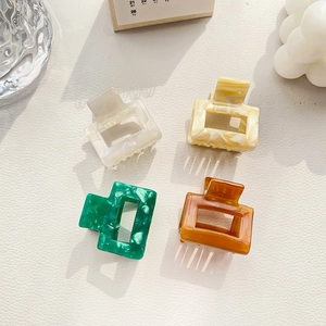 Set of four colorful acetate hair claws in creamy white, marble, and amber finishes