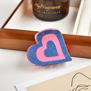 Denim blue and pink heart-shaped acetate claw clip displayed on a wooden tray