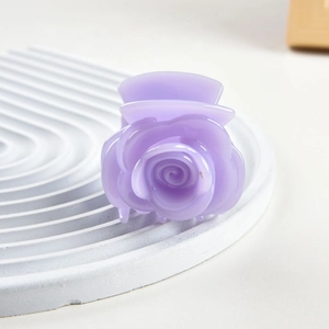 Close-up of a lilac rose hair claw clip with jelly texture on white stone display