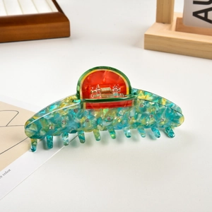 Dettaglio molletta per capelli in acetato con motivo marmorizzato e decoro anguria in strass