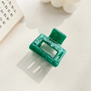 Detailed view of emerald green marbled acetic acid hair claw clip on lifestyle setting