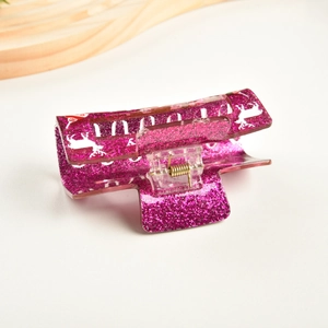 Détail macro de la pince à cheveux pailletée magenta avec motif de renne de Noël blanc