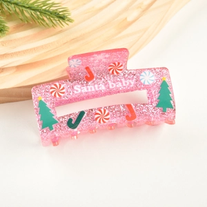 Gros plan sur la pince à cheveux en acrylique rose pailleté avec texte Santa Baby et sapin