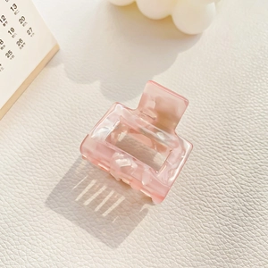 Detail of pink acetate hair claw clip with marble texture on soft white background