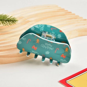 Dettaglio di una pinza per capelli verde con motivi festivi di Buon Natale stampati