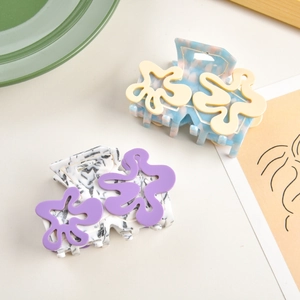 Détail de pinces à cheveux en acétate style Matisse aux motifs floraux colorés sur une table