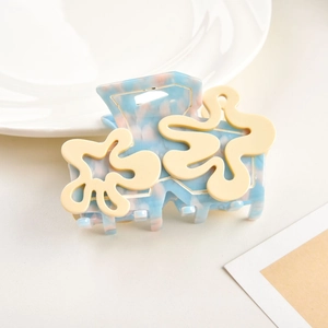 Détail de la pince à cheveux en acétate bleu avec motif floral jaune sur assiette
