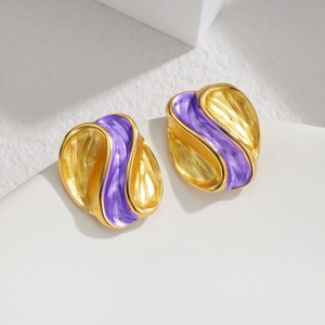 Detail of artistic purple enamel earrings with wavy gold edges on white stone