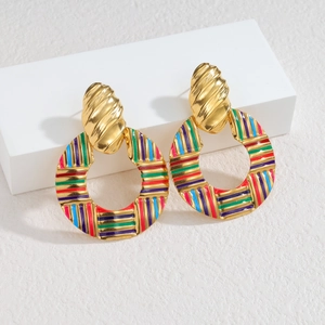 Gros plan de boucles d'oreilles rondes à rayures colorées et clous dorés texturés