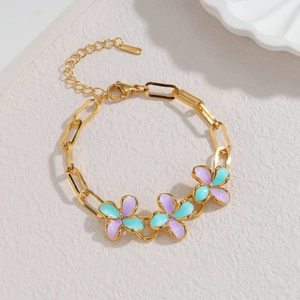 Detail van de gouden roestvrijstalen armband met paarse en blauwe emaille bloemen