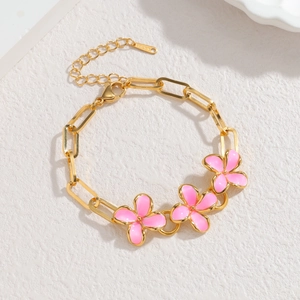Chique goudkleurige roestvrijstalen schakelarmband met roze emaille bloemen en karabijnsluiting