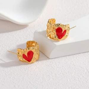 Irregular gold pleated earrings with red enamel heart design on white stone