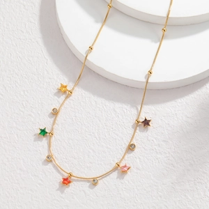 Detail of gold beaded necklace featuring colorful star pendants and clear cubic zirconia