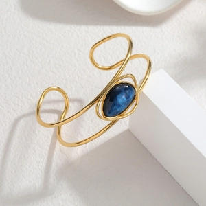 Detailed macro of vintage gold cuff featuring a teardrop blue stone and hollow lines