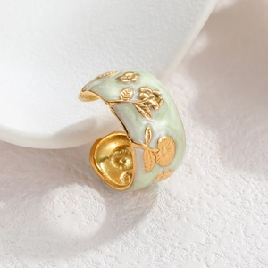 Macro shot of vintage gold flower patterns on a green enamel wide band ring