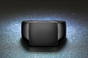 Macro detail of high-polish black stainless steel signet ring with smooth flat top surface
