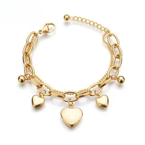 Detail of gold double-layer chain bracelet featuring heart pendants and metal beads