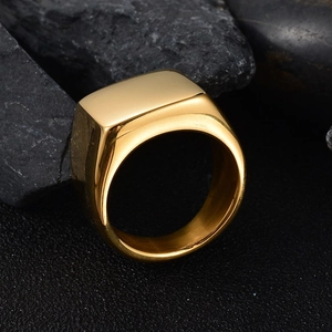 Close-up of polished gold square signet ring on a dark textured rock background