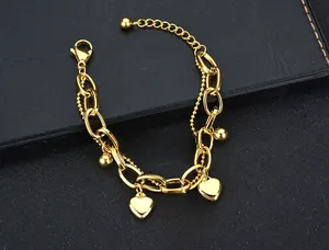 Detail view of gold stainless steel double-layer chain with heart and tree of life charms