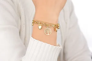 Detail of layered gold titanium steel bracelet featuring heart and tree of life charms