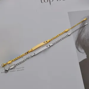 Détail des bracelets Figaro en acier doré et argenté avec plaque incurvée à cœur évidé