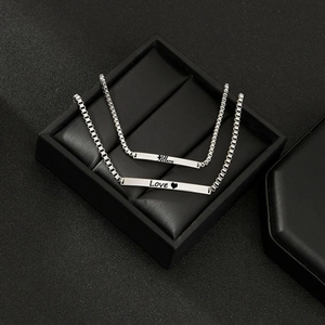 Polished silver stainless steel couple bracelets with engraved bar in a black jewelry box