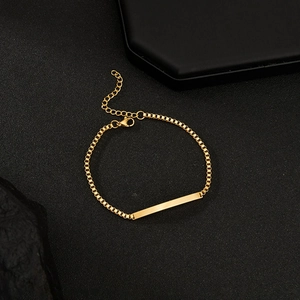Elegant gold curved bar bracelet with box chain on a minimalist black stone background