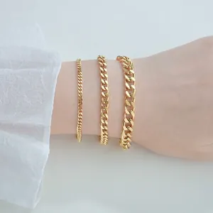 Three gold-plated stainless steel Cuban link bracelets in various widths on a wrist