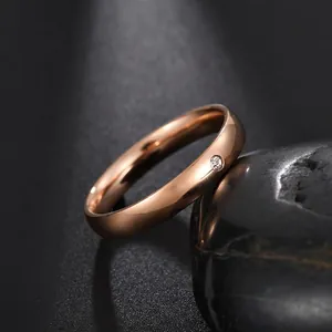 Macro detail of rose gold dome ring with a single diamond on a black pebble