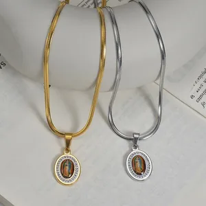 Detail of 18k gold and silver Virgin Mary oval pendants on snake chains over book pages