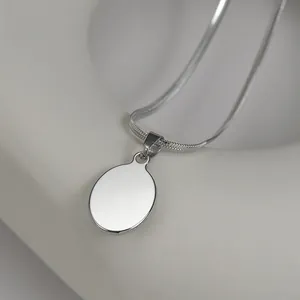 Macro view of polished silver oval pendant on a smooth snake chain necklace