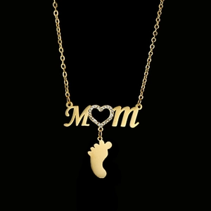Detailed shot of golden MOM necklace with a heart-shaped stone and baby feet pendant