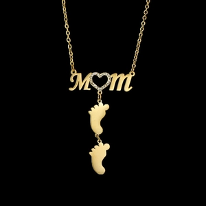 Detailed close-up of gold MOM pendant with crystal heart and baby feet charms