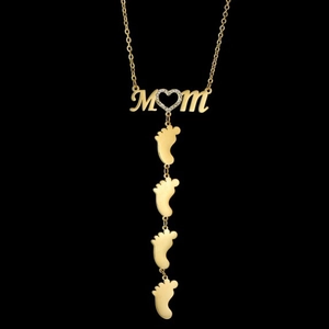 Detail of gold MOM necklace with heart crystal and four baby feet charms on black background