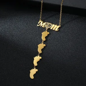 Detailed close-up of gold MOM pendant with zircon heart and four small feet charms
