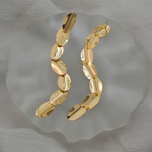 Macro view of gold-plated oval fringe drop earrings with polished mirror finish details