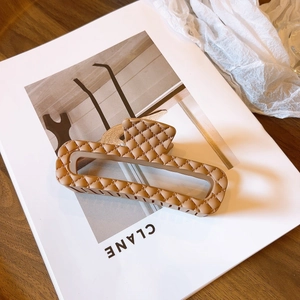 Dettaglio della grande molletta opaca kaki con elegante design a trama a rombi in rilievo