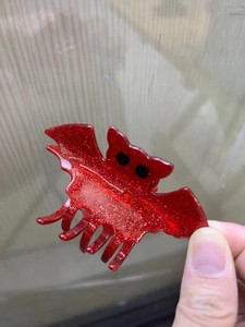 Détail d'une pince à cheveux chauve-souris rouge pailletée avec petits yeux