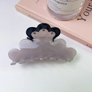 Macro detail of bicolored cloud-shaped hair claw clip with glossy finish and wavy edges