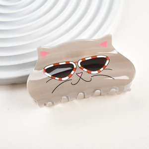 Détail d'une pince à cheveux grise en acrylique en forme de chat avec lunettes rouges