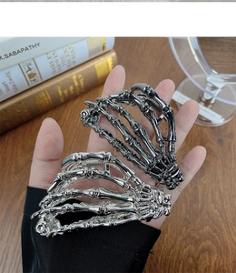 Detailed view of silver and gun-black skeleton hand hair claws on a vintage desk