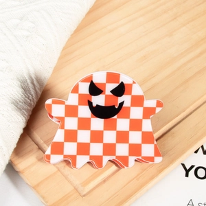 Détail de la pince à cheveux fantôme avec motif en damier orange et blanc sur bois