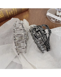 Close-up of skeleton hand hair claws in silver and gunmetal alloy on vintage background