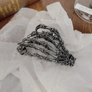 Close-up of skeleton hand hair claw clip in dark silver metal on vintage paper